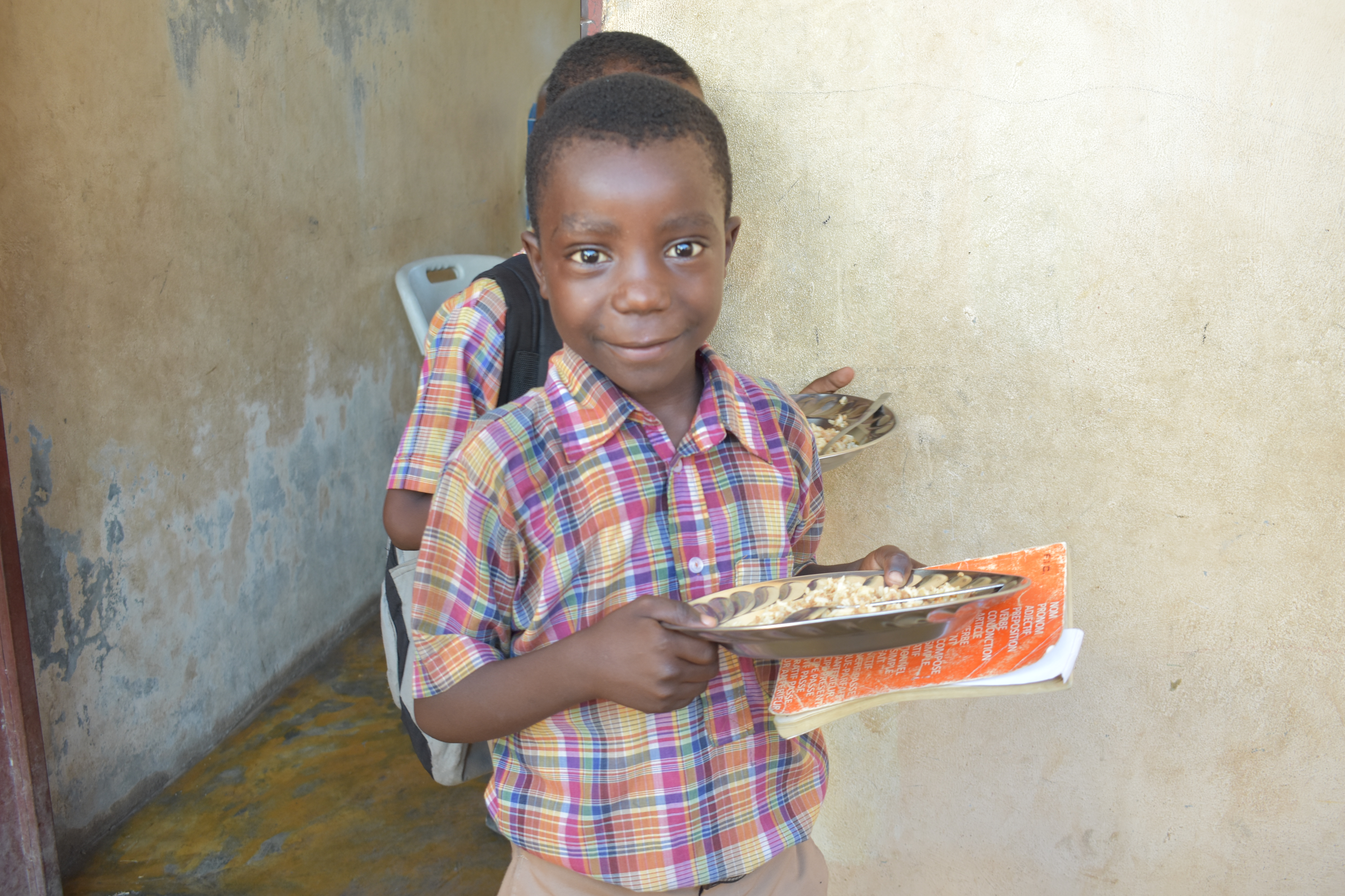 Haitian child carrying his lunch plate